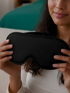 Woman holding a black sleep mask with a blurred background