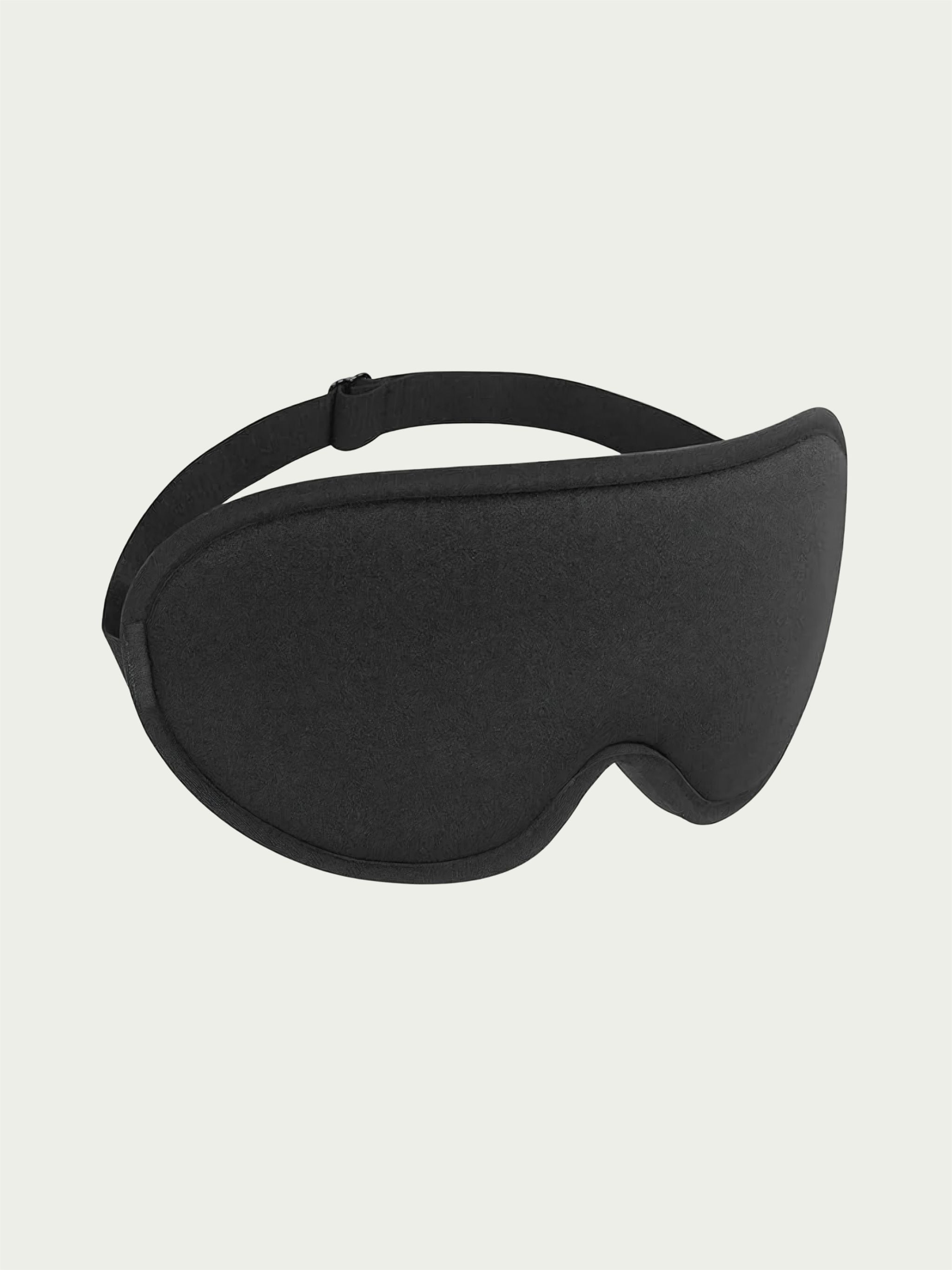 A black sleep mask with a curved design and adjustable strap is centered against a light gray background, conveying comfort and relaxation.
