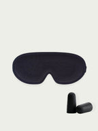 Black sleep mask  and black ear plugs on a light beige background 